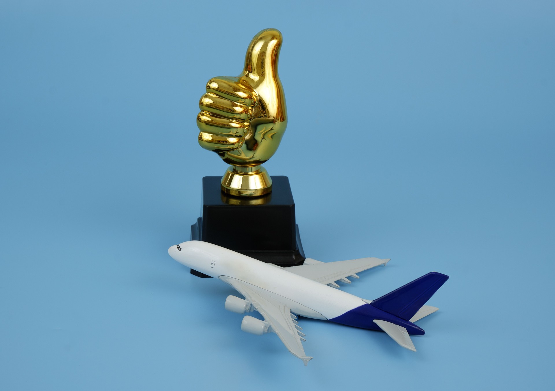 Airplane and thumbs up trophy cup on blue background.
